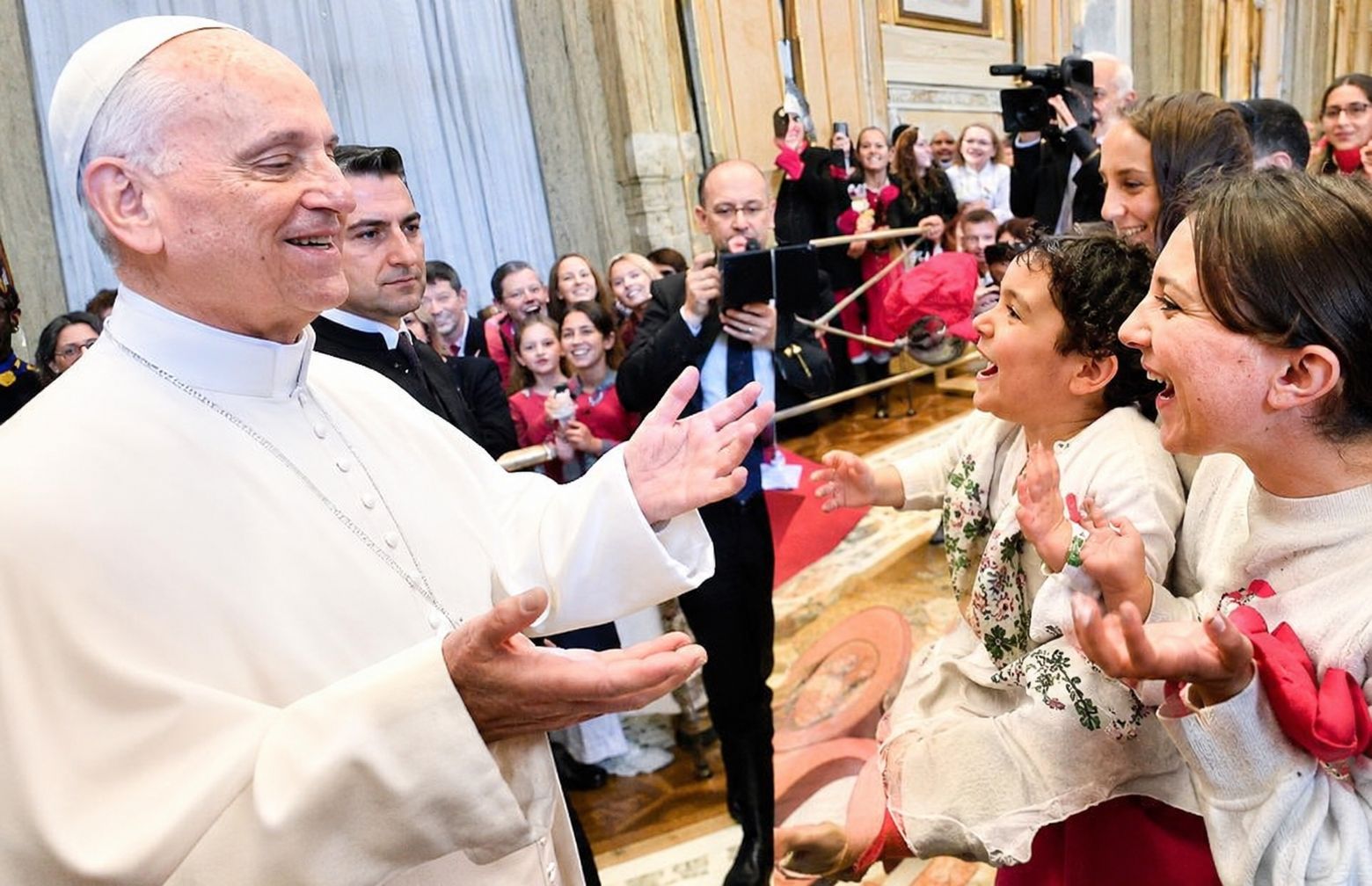 Pope Leo XIV making the viral "6-7" TikTok hand gesture while smiling and interacting with children during a Sunday audience at the Vatican